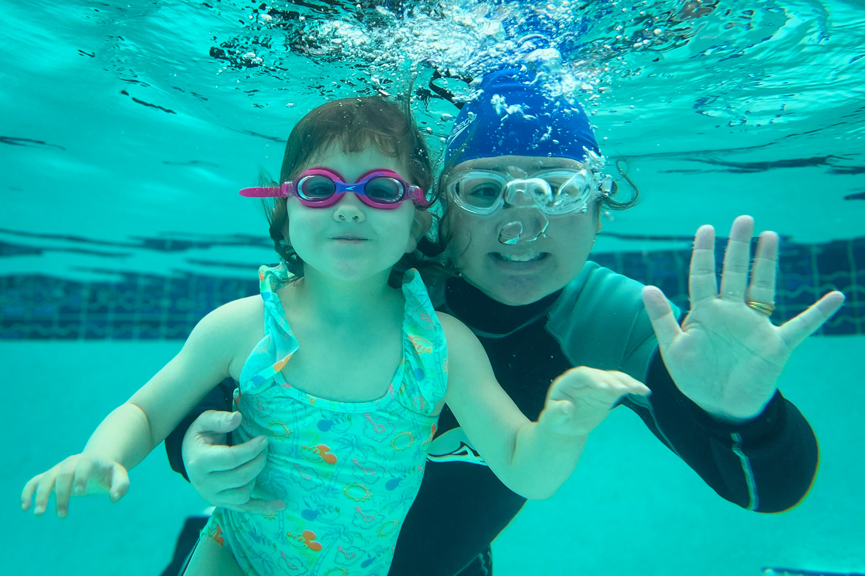 Instructor and toddler face-to-face underwater during a lesson